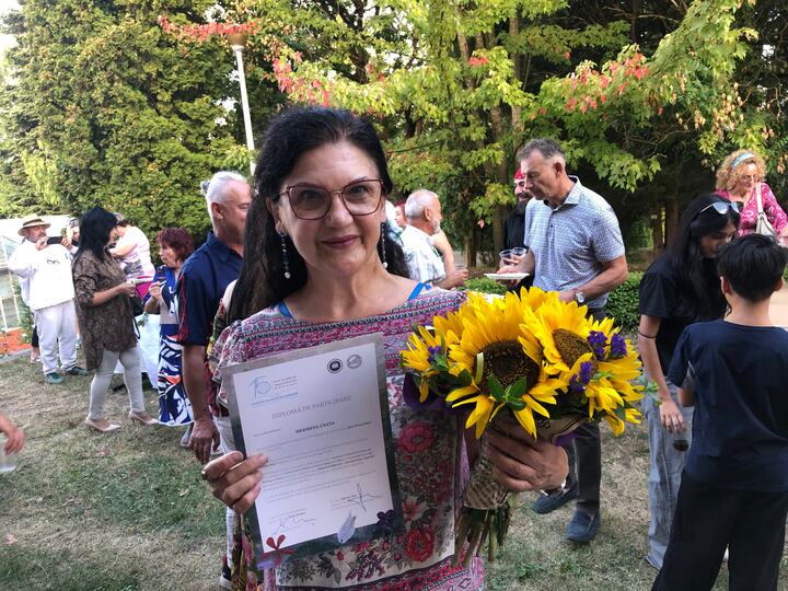 Participantă cu diplomă și flori în grădină
