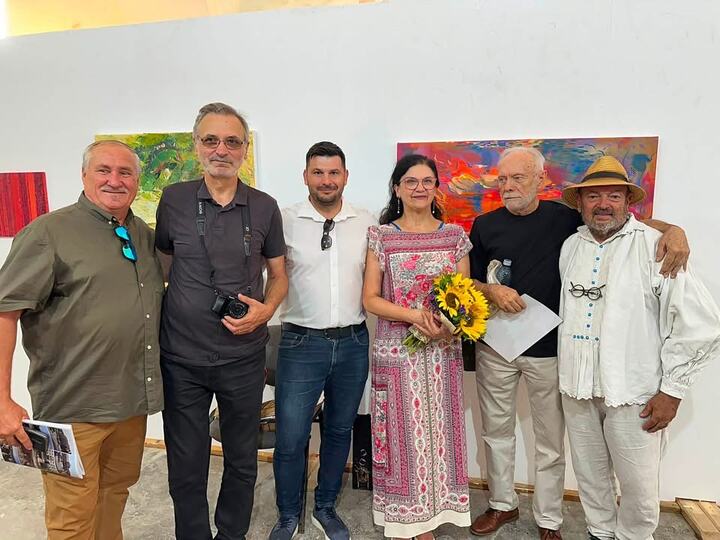 Grup de participanți fotografiat în fața lucrărilor expuse