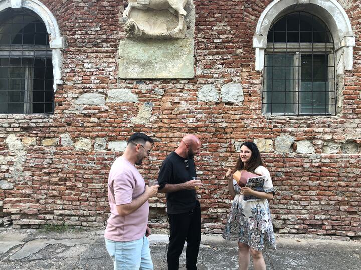 Participanți discutând lângă zidul vechi al clădirii